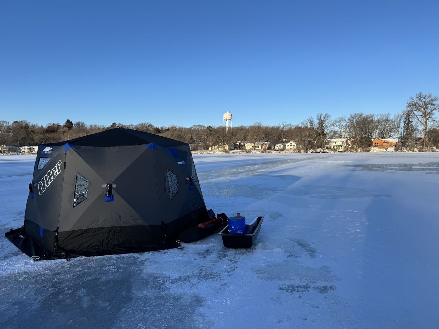 The Otter Pro Resort hub set up on the ice with a sled and bucket beside it