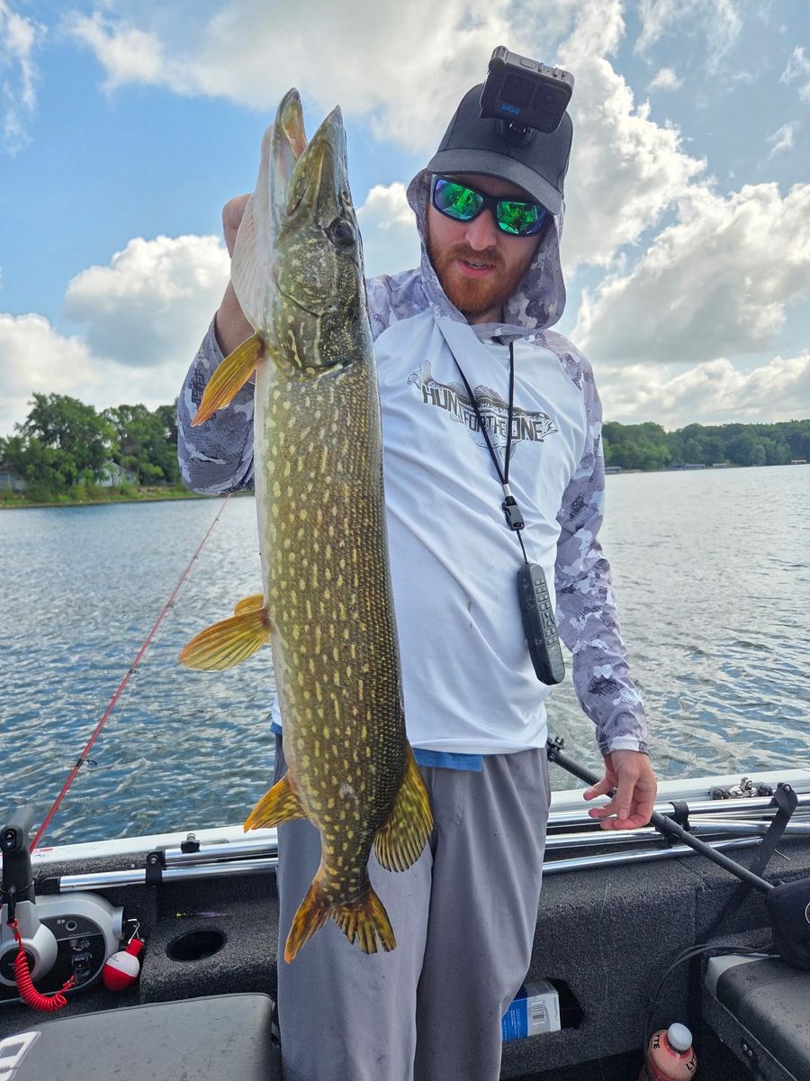 Scott holding a northern pike in the boat on a sunny day