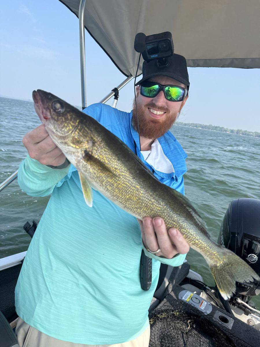 Scott holding a walleye in the boat, head-mounted GoPro on his cap